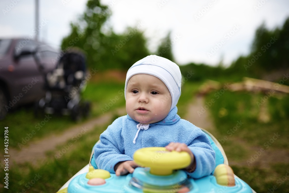 Crying cute baby in baby walker walks outdoors Crying cute baby in baby walker walks outdoors