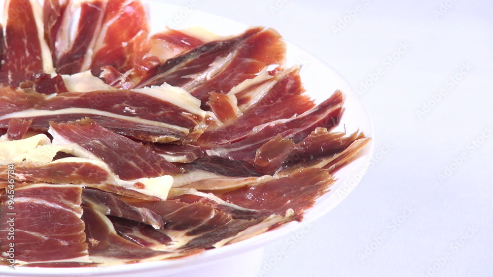 view of pile of typical spanish iberico ham sliced on dish rotating spinning on white background
view of pile of typical spanish iberico ham sliced on dish rotating spinning on white background
