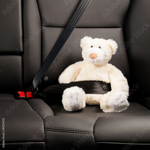 Teddy bear strapped in with seat belt in back seat of car Stock Photo