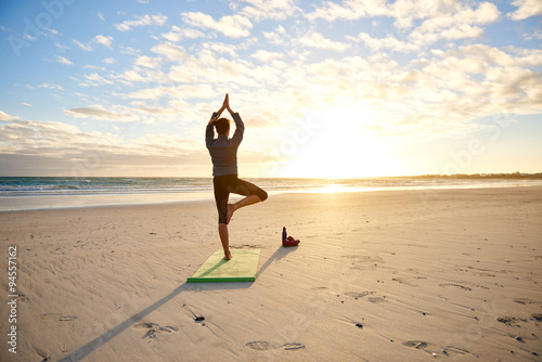 Fototapeta Naklejka Na Ścianę i Meble -  Woman performing a balancing yoga pose on beach
