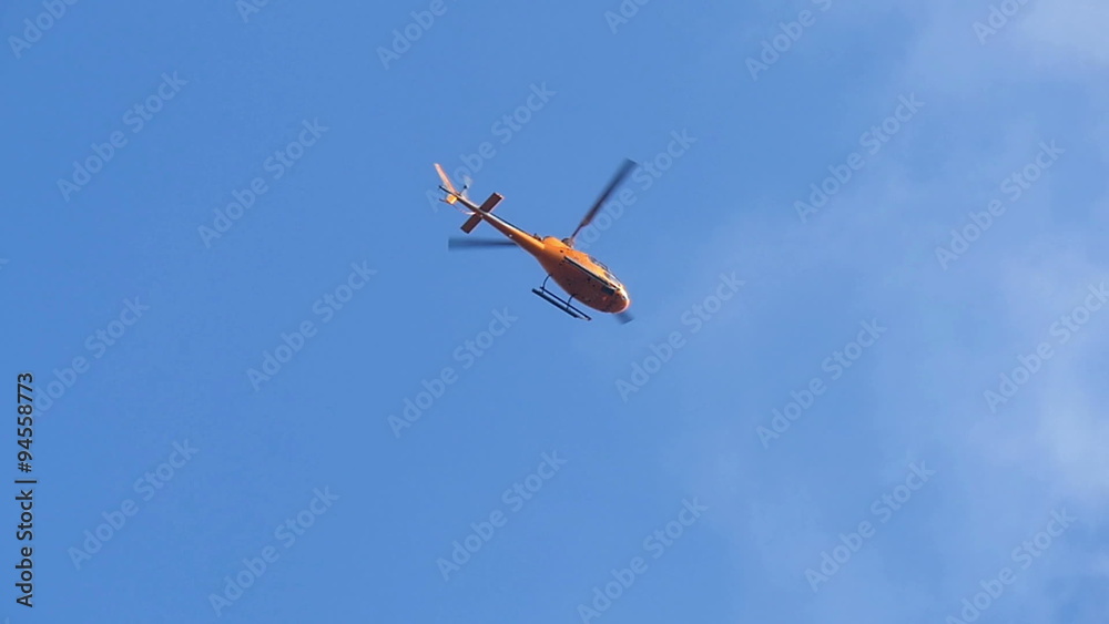 A brown helicopter going through the city of London. With its propeller turning around under the blue sky A brown helicopter going through the city of London. With its propeller turning around under the blue sky