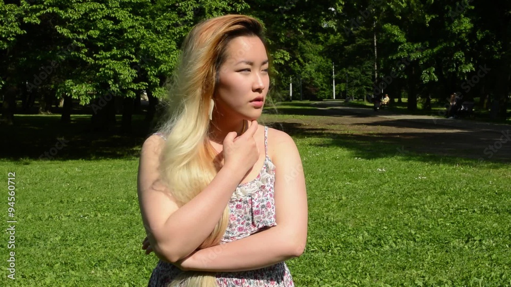 young attractive asian woman thinks with the based arms in the park young attractive asian woman thinks with the based arms in the park