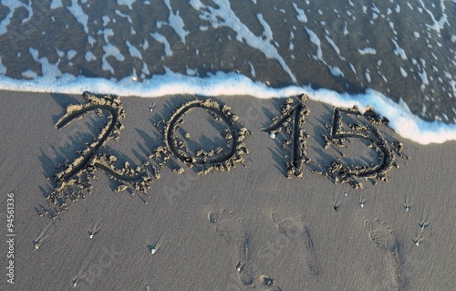 inscription year 2015 in the sand of the sea with waves