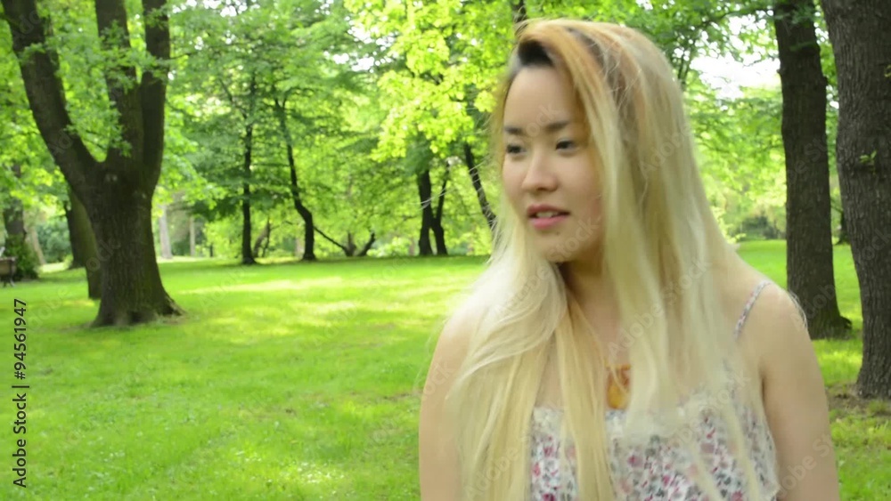 young asian attractive smiles woman walks in the park - emotions - steadicam young asian attractive smiles woman walks in the park - emotions - steadicam