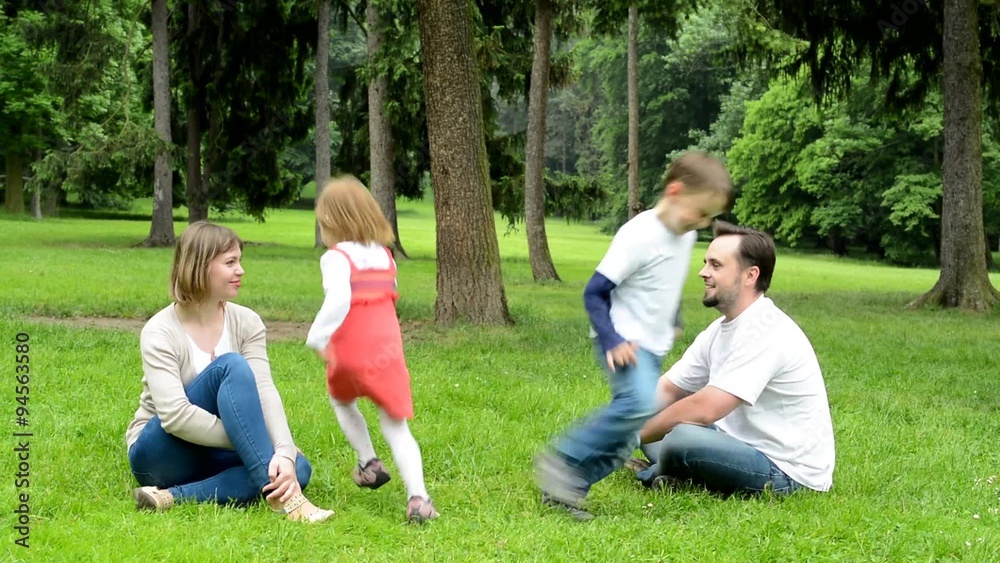 family (middle couple in love, cute girl and small boy) relax together in park - children running around parents family (middle couple in love, cute girl and small boy) relax together in park - children running around parents