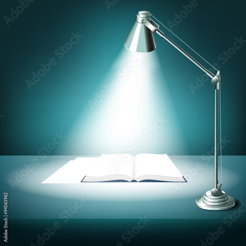 Opened book on table with desk lamp