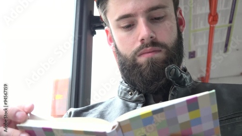 young handsome hipster man travel by tram and reads a book - closeup photo