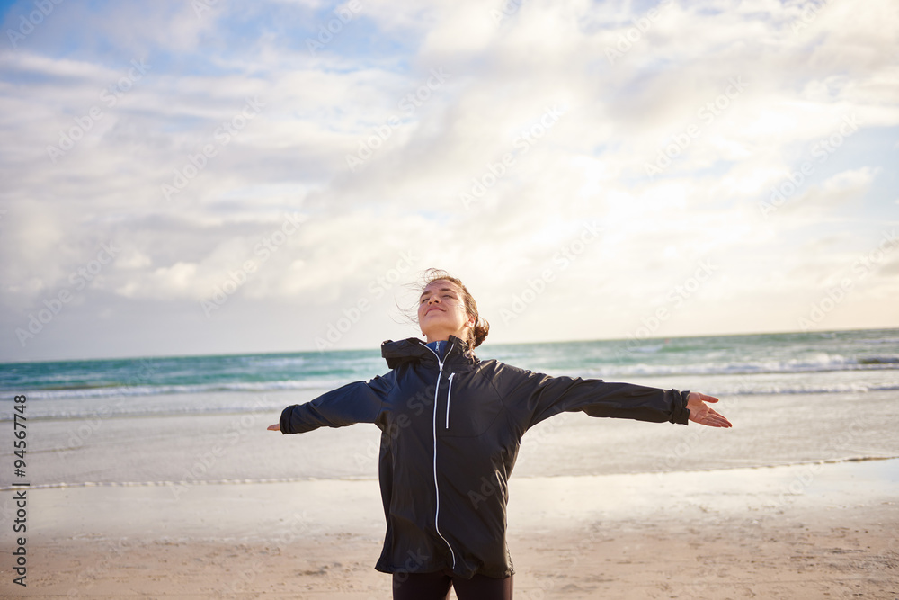 Young woman with her arms outstretched on a winter beach Young woman with her arms outstretched on a winter beach