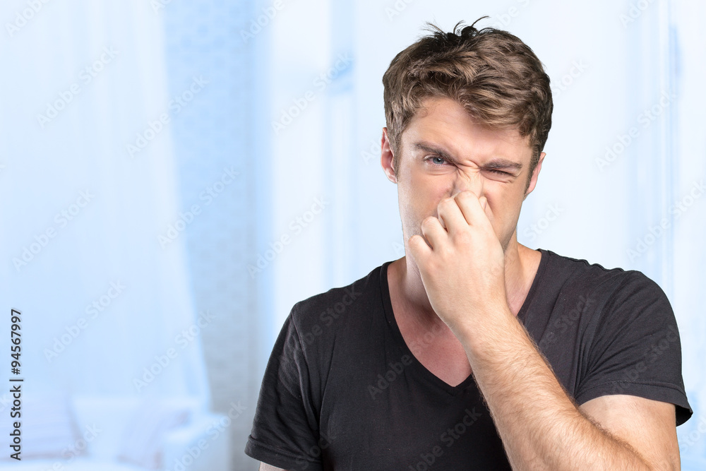 Young Man holding his nose against a bad smell - obrazy, fototapety, plakaty 