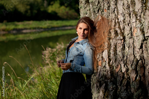 молодая девушка с длинными волосами у озера в солнечную погоду