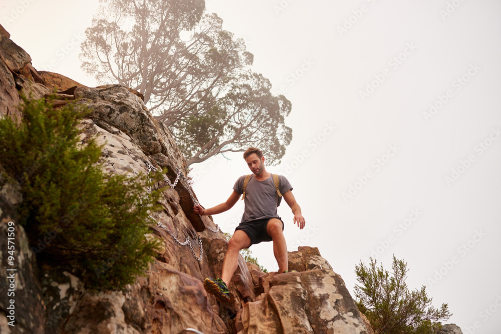 Young hiker climbing down some difficult rocks Young hiker climbing down some difficult rocks