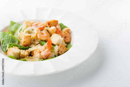 Caesar salad with shrimps on the white background horizontal