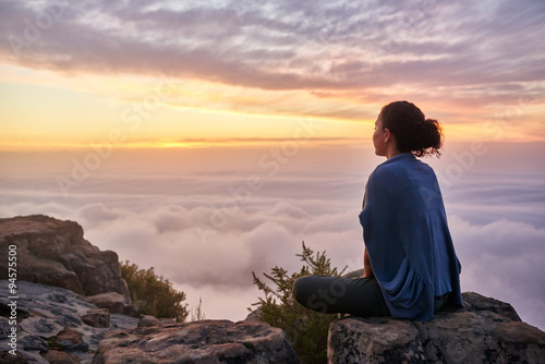 Woman on a mountain top looking at morning clouds