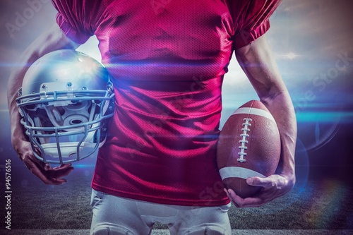 Composite image of american football player holding ball and helmet © vectorfusionart