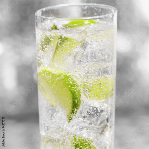Glass of soda with ice and sliced fresh lime photo
