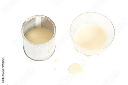 Condensed milk with sugar in glass bowl and tin can