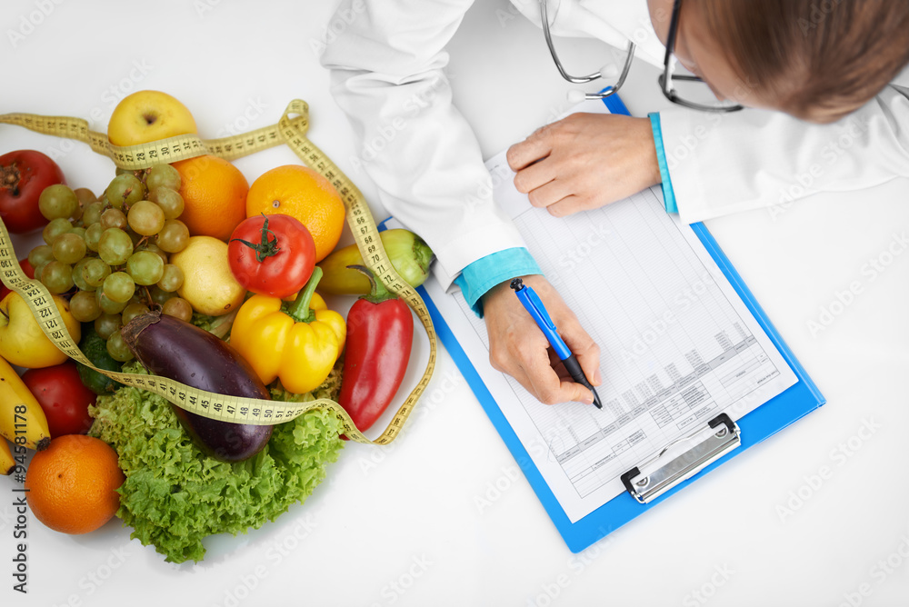 Doctor therapist writing case development form sitting at the desk in hospital. Female nutritionist prescribing diet to patient. Doctor therapist writing case development form sitting at the desk in hospital. Female nutritionist prescribing diet to patient.