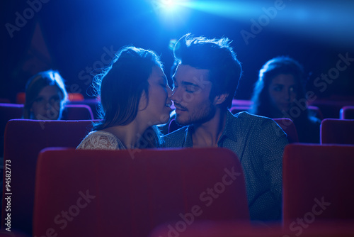 Young loving couple kissing at the cinema
