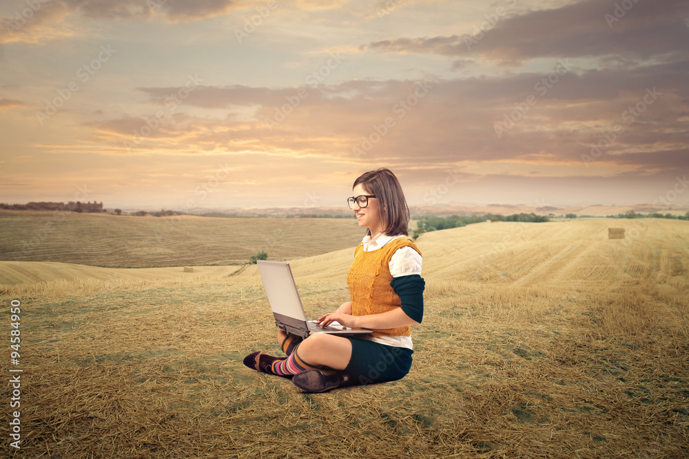 Woman sitting in the countryside using a laptop