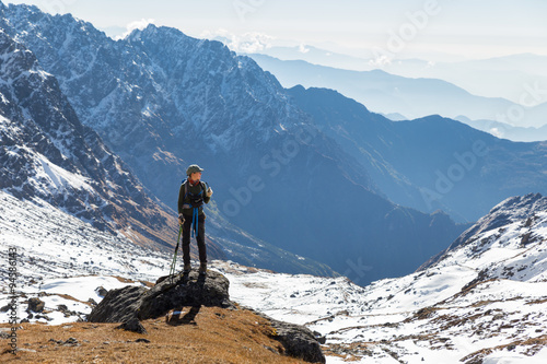 Young woman tourist backpacker standing rock mountain edge.
