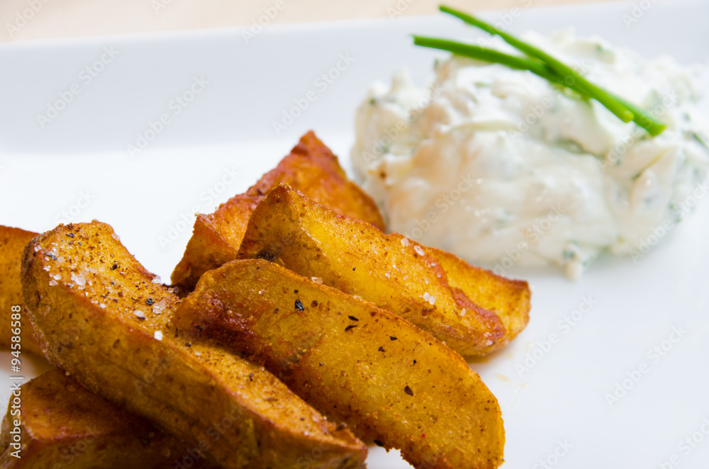 Fried potatoes on white plate with creamy dip Fried potatoes on white plate with creamy dip