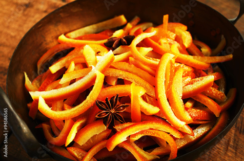 Cooking candied orange peels with spices in cooper bowl