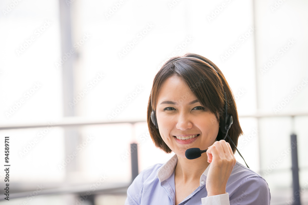 Asian Business woman talking using her headset in the office Asian Business woman talking using her headset in the office
