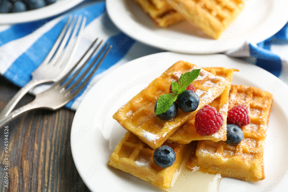 Sweet homemade waffles with forest berries and sauce on table background Sweet homemade waffles with forest berries and sauce on table background