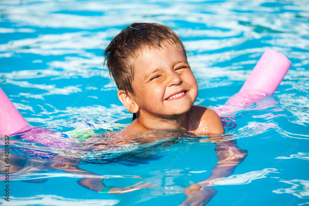 Close-up of boy learning to swim with pool noodle