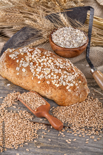 Bread from rye and healthy grains on an old rustic table with a sickle in the background