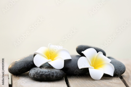 Composition of pebbles and fragipani flower on wooden background