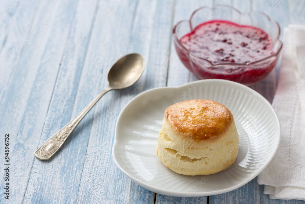 Freshly baked homemade scone with raspberry jam on a white plate, selective focus Freshly baked homemade scone with raspberry jam on a white plate, selective focus