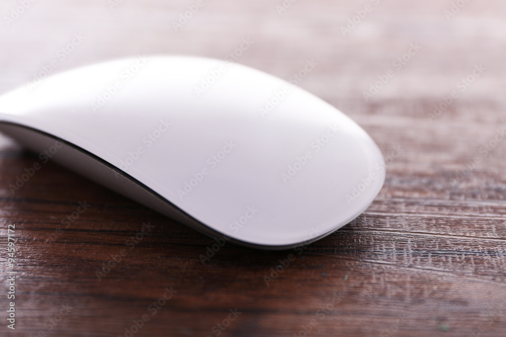 White wireless computer mouse on wooden background White wireless computer mouse on wooden background