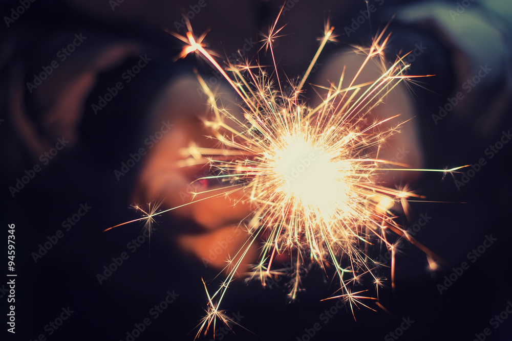 hands holding a burning sparkler