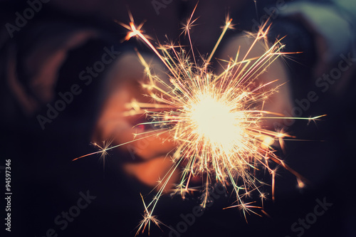 hands holding a burning sparkler photo