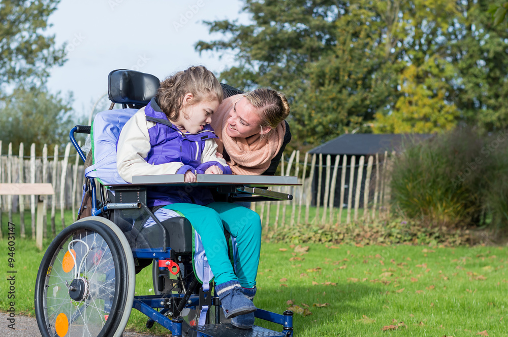 Disability/ A disabled child in a wheelchair with a carer outside