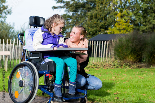 Foto Disability/ A disabled child in a wheelchair with a carer going for a walk