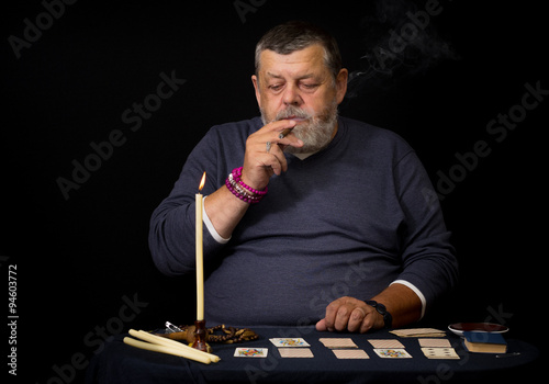 Photography Portrait of an old man smoking cigar before cartomancy