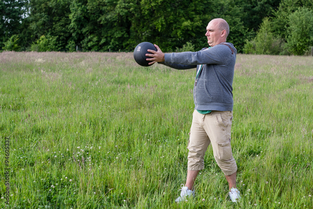 Mann trainiert Draußen mit einem 3 Kilo Medizinball Mann trainiert Draußen mit einem 3 Kilo Medizinball