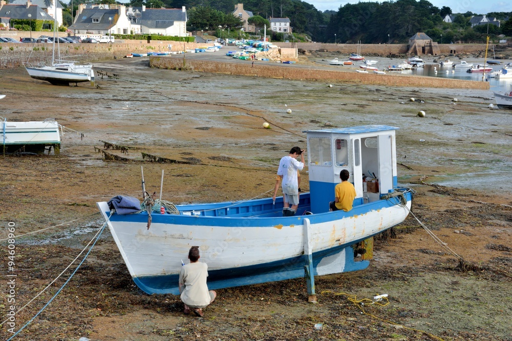 Une famille entretien son bateau de pêche à marée basse