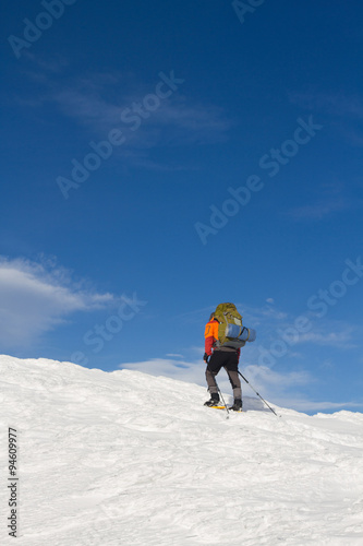 Winter hiking in the mountains on snowshoes with a backpack and tent.