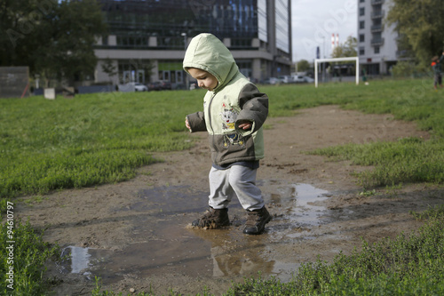 Two years child walk and playing in mud puddle