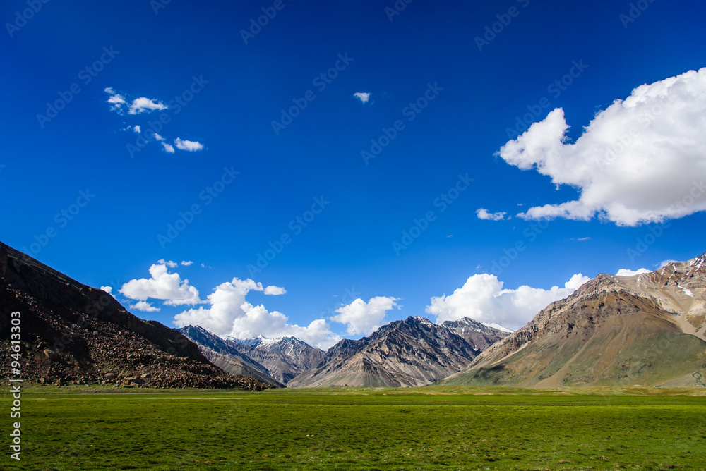 Beautiful landscape of green field, mountain and blue sky.