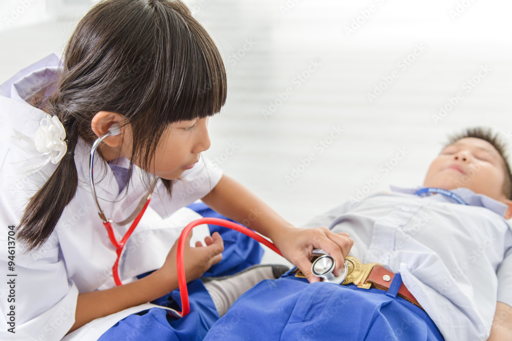 Obraz premium Adorable Asian child dressed as doctor playing with her brother