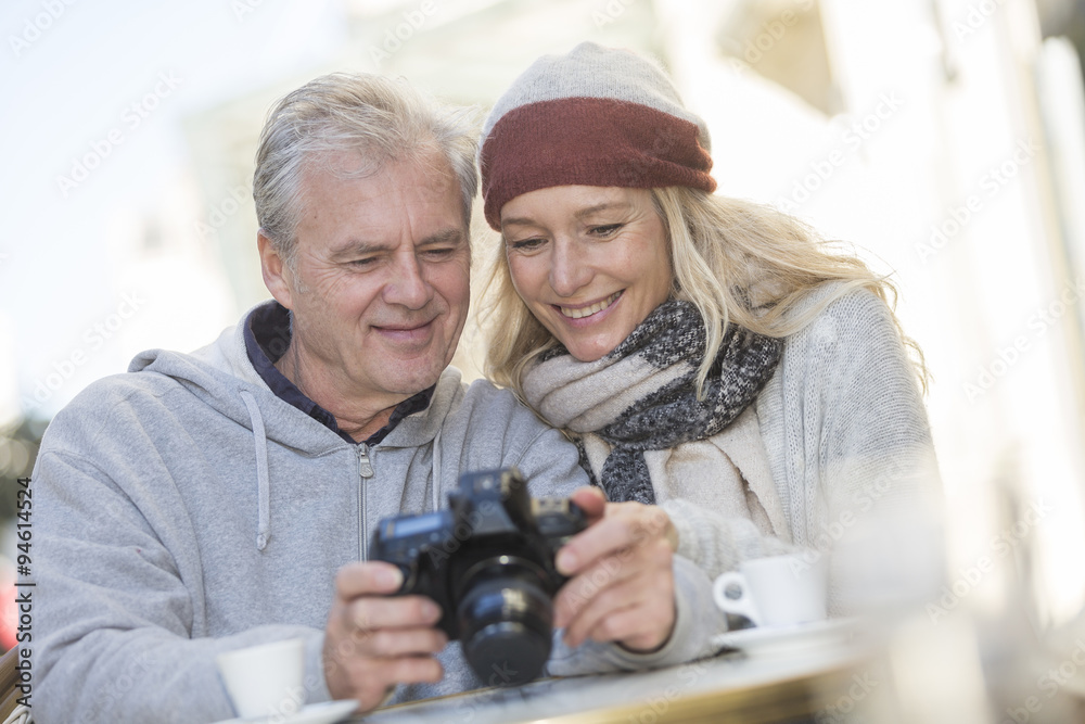 Mature couple using a camera at a bar terrace Mature couple using a camera at a bar terrace