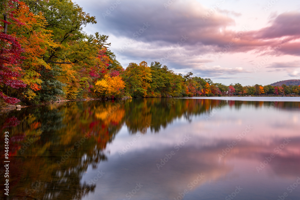 Fototapeta premium Fall foliage reflects in Hessian Lake at sunset, near Bear Mountain, NY