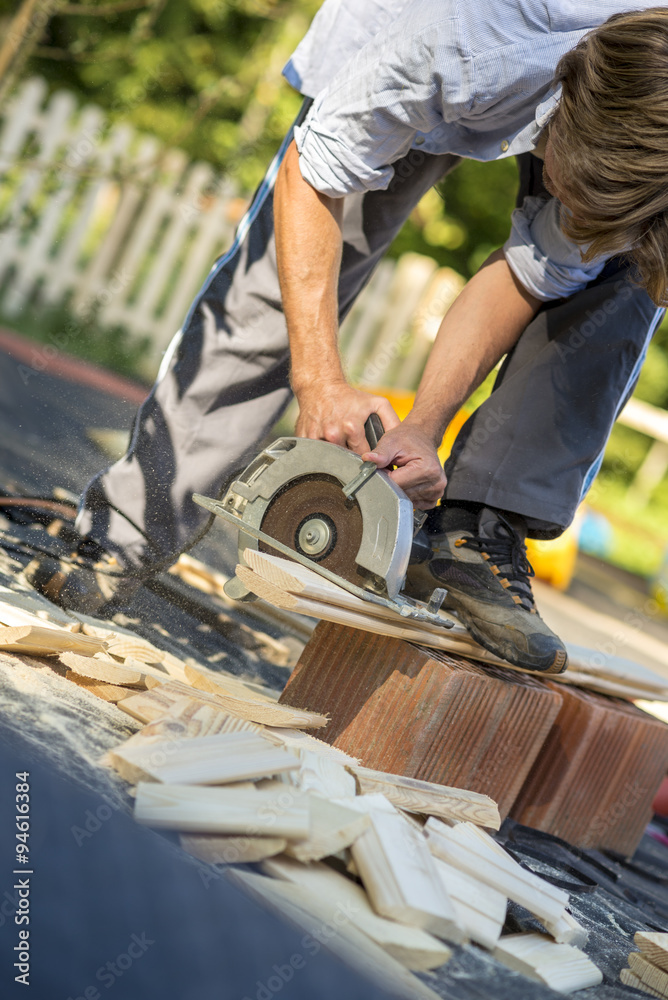 Young man working in his back yard using circular saw