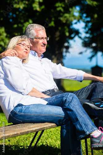 Senioren Mann und Frau ruhen sich auf Bank aus und genießen ihre Ferien © Kzenon