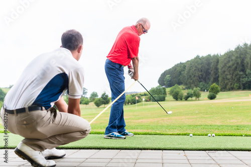 Golflehrer trainiert Golfer auf Driving Range