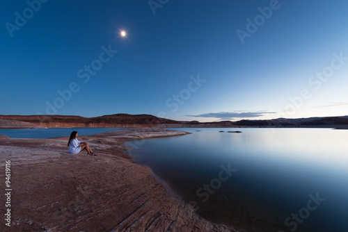 Single Woman sitting by the lake under the moon light